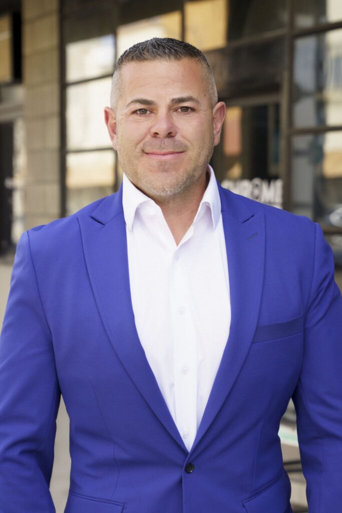 Man in blue suit smiling outdoors