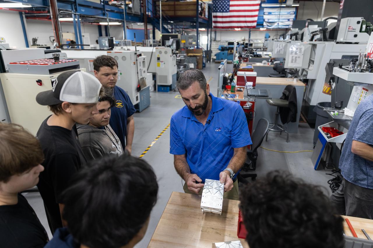 Instructor demonstrating machining to students in workshop