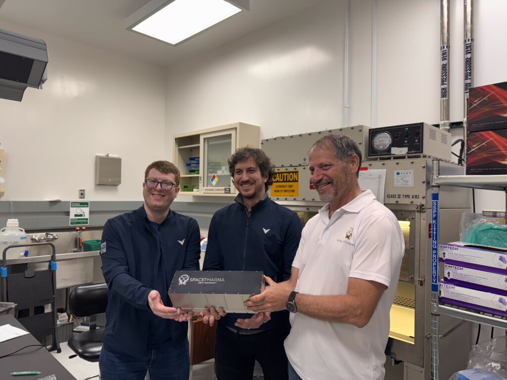 Three scientists smiling in lab holding SpacePharma equipment