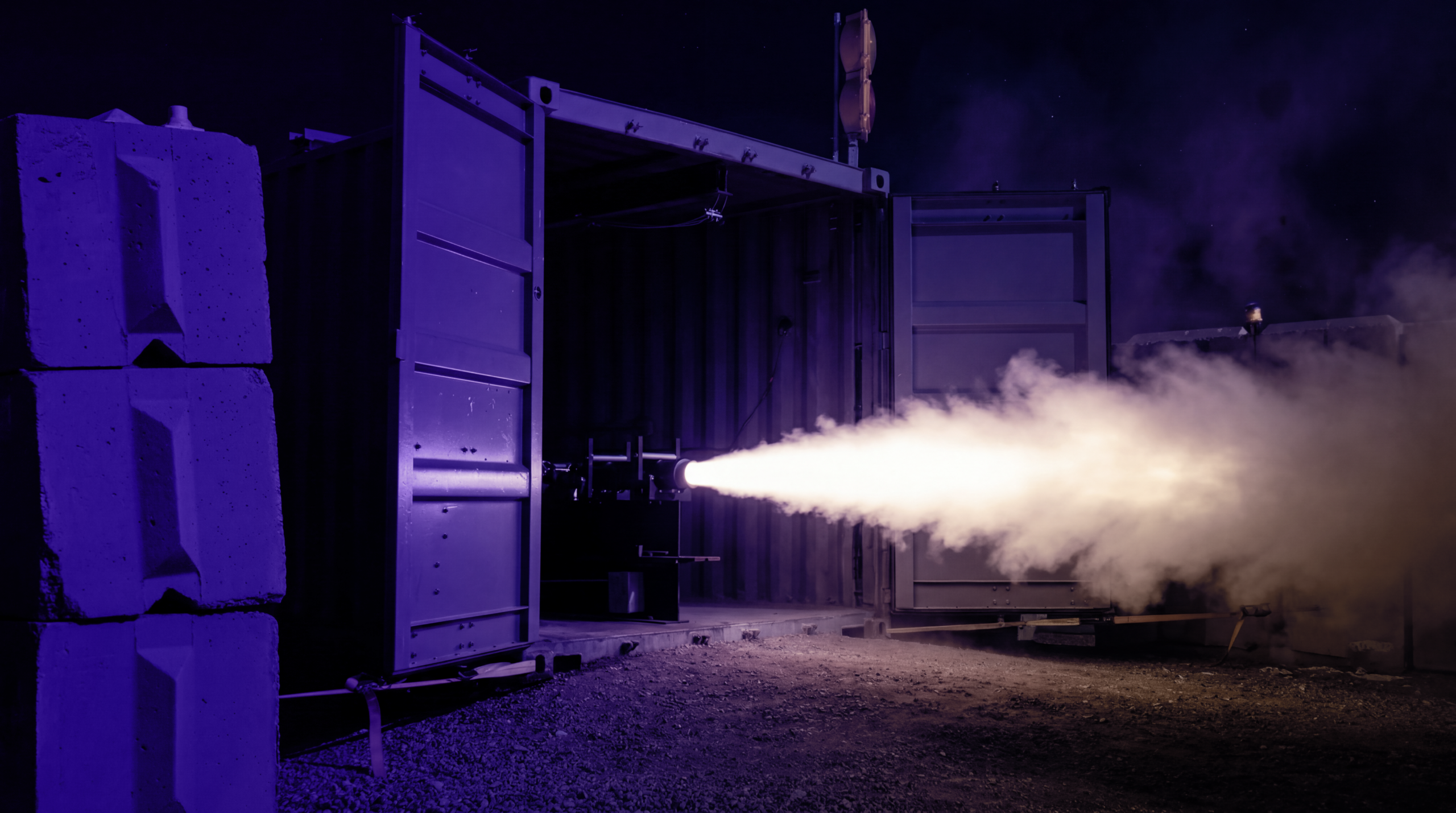 Rocket engine test in dark industrial setting.