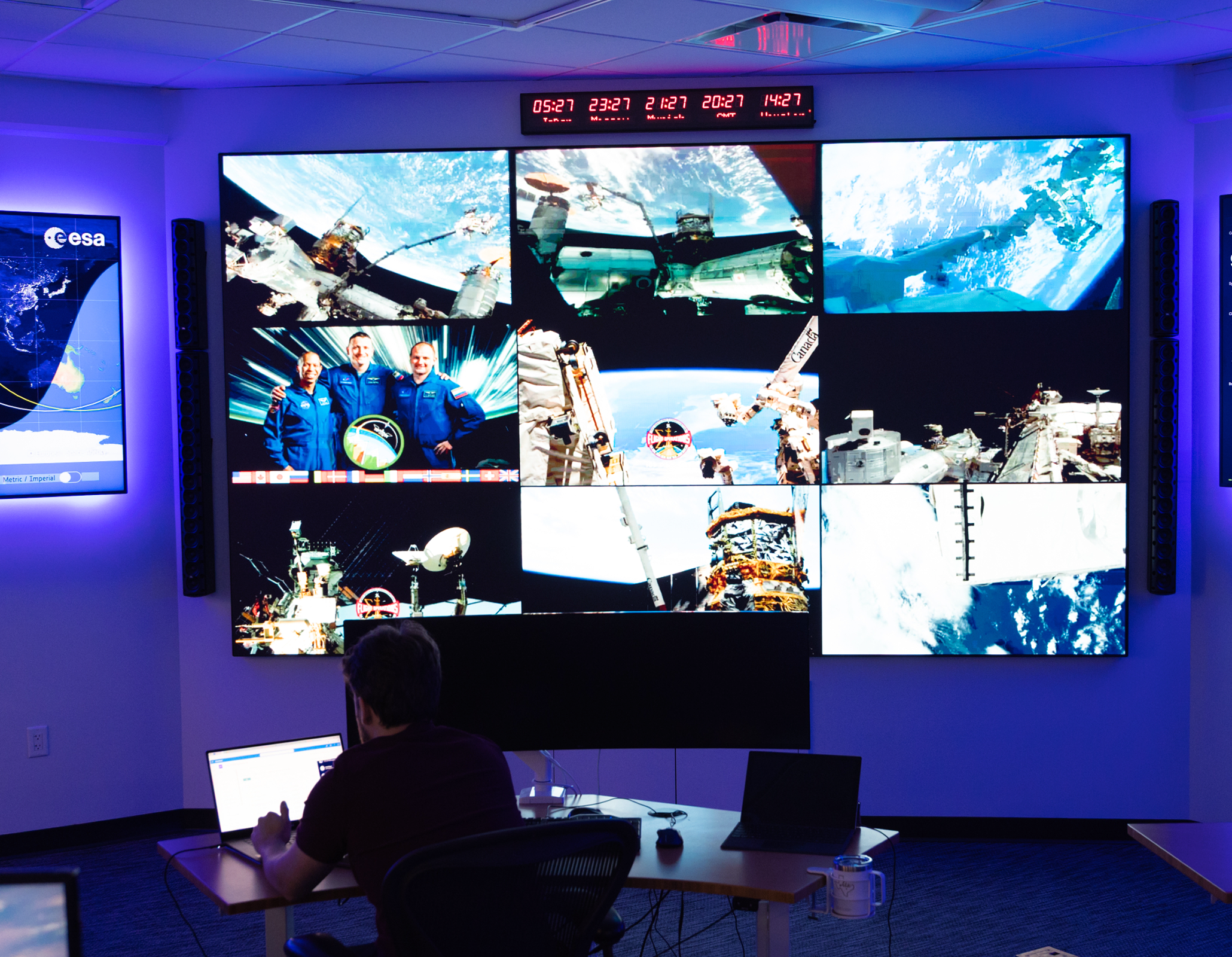 Mission control room with multiple screens displaying space images.