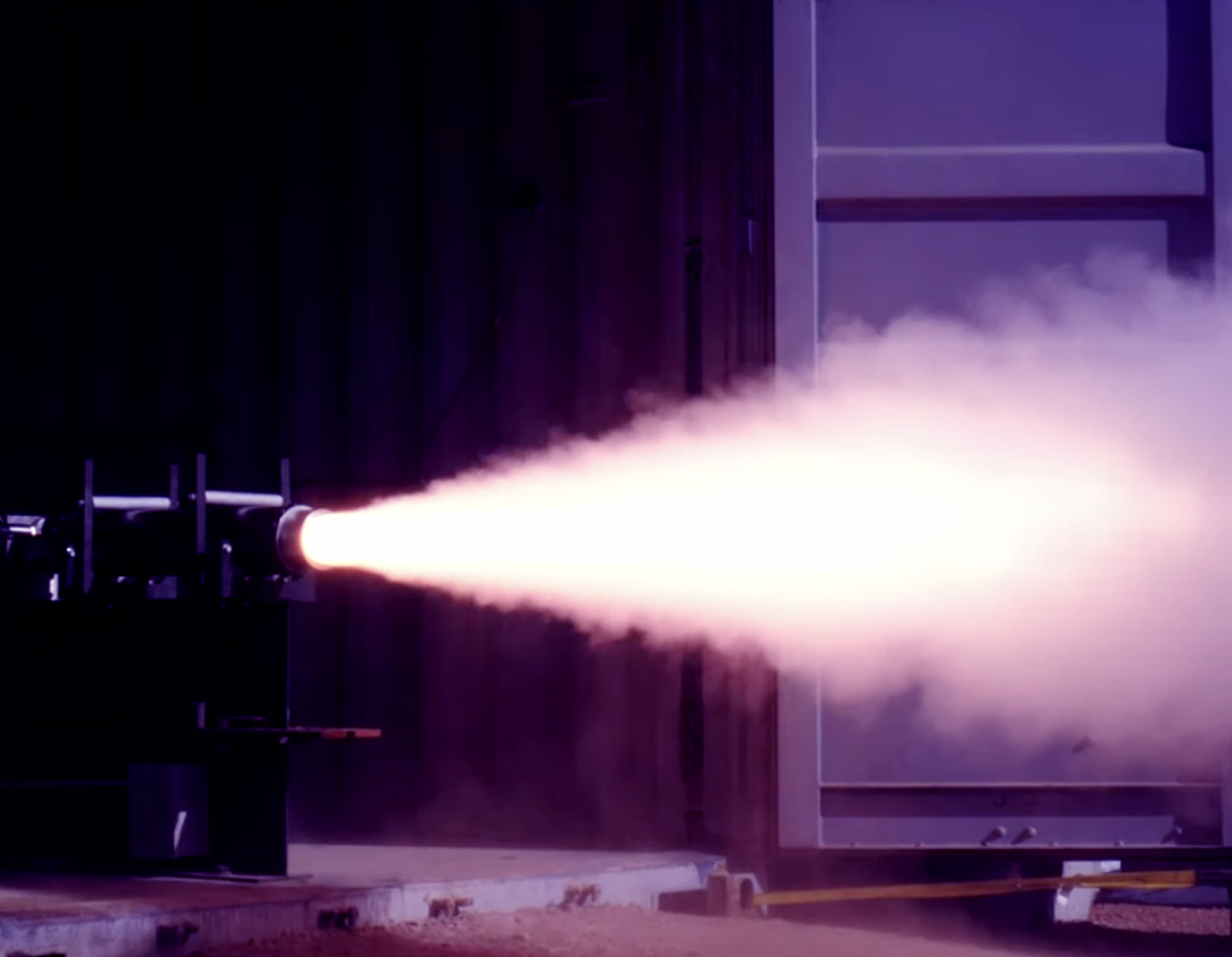 Rocket engine test firing with flame and smoke.