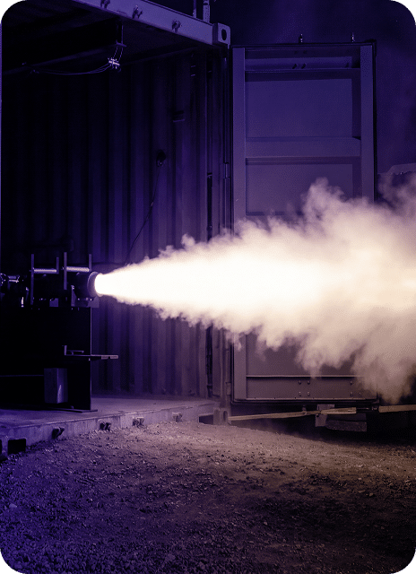 Rocket engine testing with fiery exhaust plume.