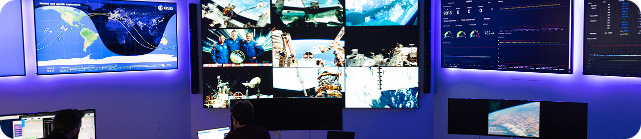 Mission control monitors displaying space missions and data.