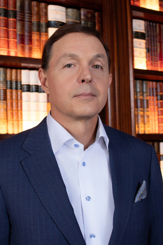 Person in suit standing by bookshelf