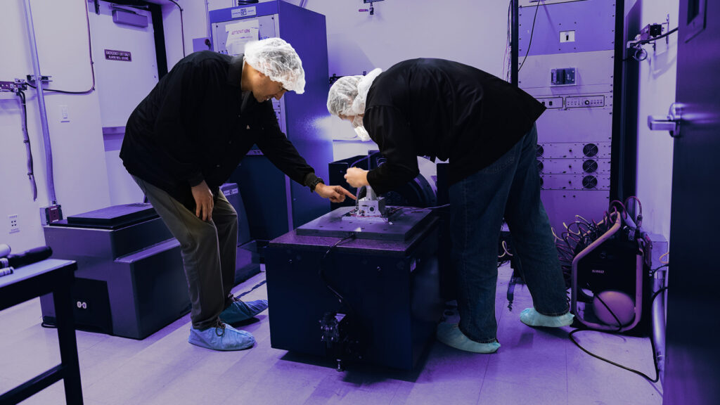 Technicians inspect equipment in a cleanroom laboratory.