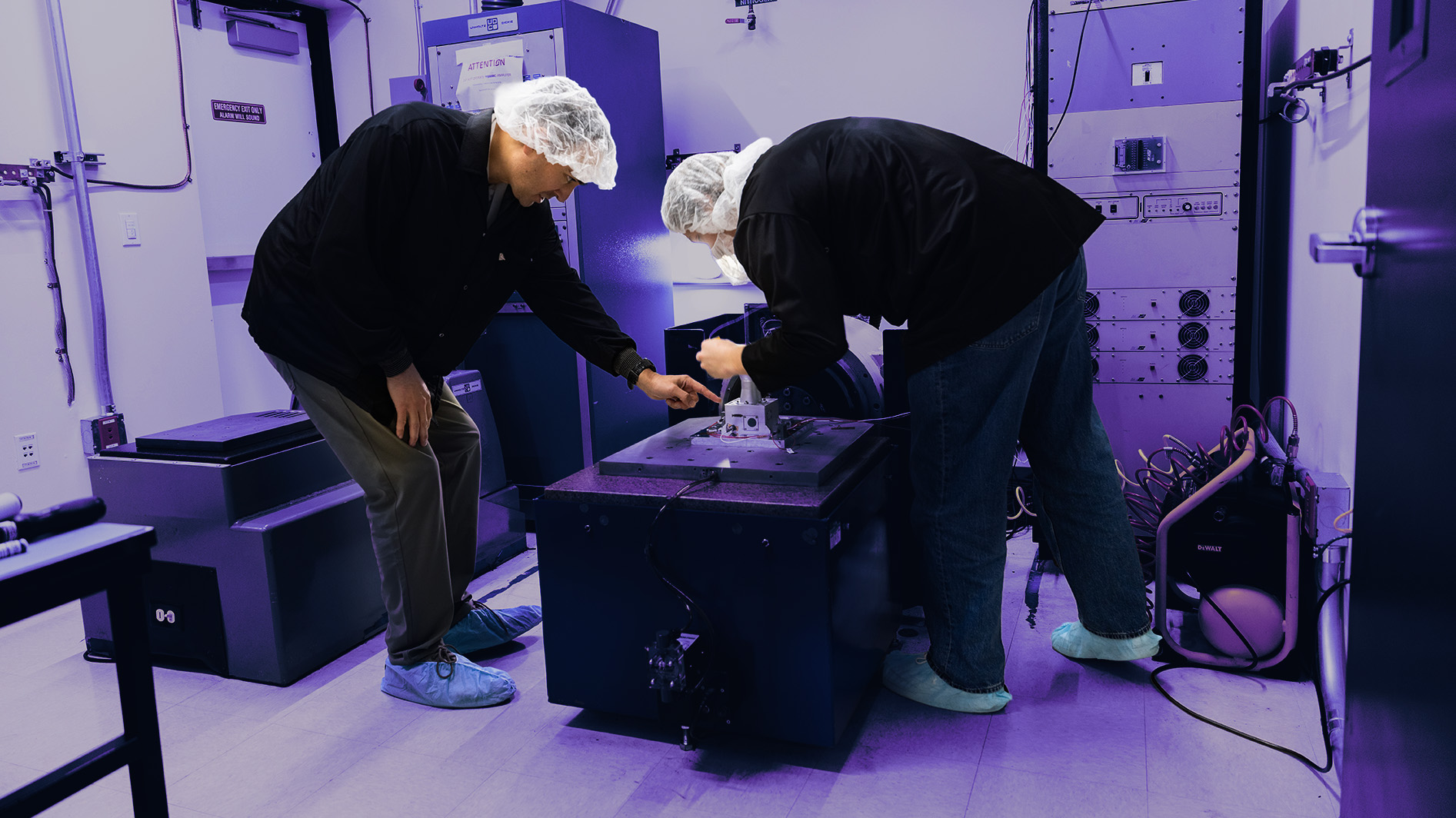 Technicians inspect equipment in a cleanroom laboratory.